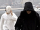 Deux membres du mouvement islamique radical de l'assassin de Theo van Gogh cachent leurs visages avant de se rendre au procès le 27 jullet 2005.Photo : AFP