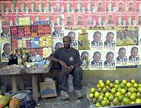 Un marchand de fruits et de légumes s'est installé, le 22 décembre dernier, devant les affiches électorales de plusieurs candidats à la présidentielle, à Port-au-Prince. (Photo: AFP)