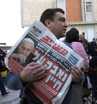 Devant l'hôpital Hadassah, où se trouve Ariel Sharon, un homme porte des journaux israéliens titrant sur l'hospitalisation du Premier ministre. (Photo: AFP)