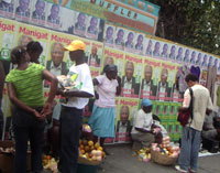 Des vendeurs d'oranges devant les affiches électorales.(Photo : Manu Pochez/RFI)