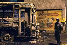 Un policier garde les restes d'un bus calciné après une attaque dans le quartier de Jardim Tremembe, au nord de Sao Paulo, le 16 mai 2006. (Photo: AFP)
