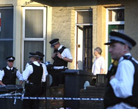 Des policiers, devant le domicile de personnes arrêtées, au 386, Forest Road, à Walhamstow (nord de Londres). Les perquisitions se poursuivent. 

		(Photo: AFP)