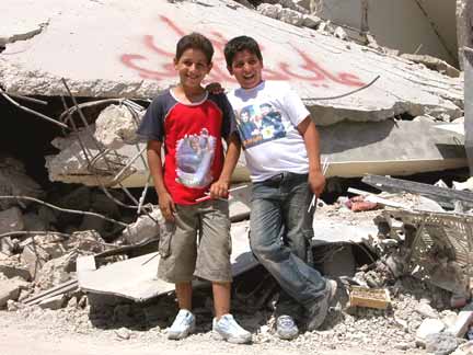 Le 23 août : A Yarine, au sud Liban, les enfants prennent la pose face au photographe devant les décombres. Sur leurs t-shirts : kung-fu (à gauche) et le leader du Hezbollah (à droite). &#13;&#10;&#13;&#10;&#9;&#9;(Photo : Bertrand Haeckler/RFI)
