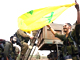 Alors que ces soldats israéliens quittent le sud du Liban, l'un d'entre eux brandit un drapeau du Hezbollah saisi au cours des combats.(Photo: AFP)