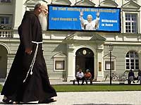 A Altötting (sud de l'Allemagne), ce moine franciscain passe devant une affiche de bienvenue à Benoît XVI. Le Saint-Père y célèbrera une messe en plein air le 11 septembre. 

		(Photo: AFP)