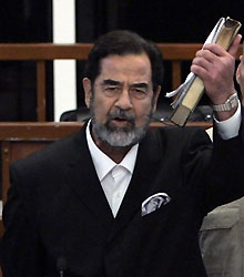 Brandissant un exemplaire du Coran, Saddam Hussein manifeste sa colère à l'énoncé du verdict le comdamnant à mort par pendaison. 

		(Photo: AFP)