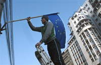 Un ouvrier roumain hisse le drapeau de l'Union européenne sur la Place de l'Université à Bucarest. 

		(Photo : AFP)