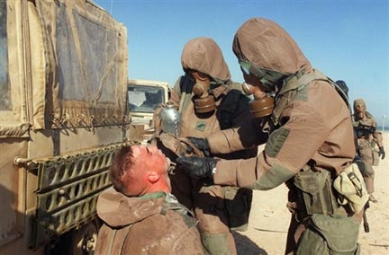 Deux soldats avec des masques à gaz s'entraînent à décontaminer un de leur camarade lors d'un exercice d'attaque chimique pendant la guerre du Golfe. (Photo : AFP)