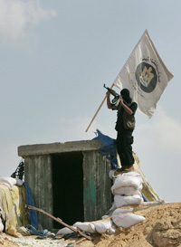 Un militant palestinien plante un drapeau du Hamas sur le toit du quartier général des forces loyales au président Abbas, ce 13 juin à Gaza. &#13;&#10;&#13;&#10;&#9;&#9;(Photo : Reuters)