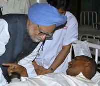 Le Premier ministre indien Manmohan Singh (g) s'est rendu au chevet des victimes à Ahmedabad le 28 juillet.(Photo : Reuters)
