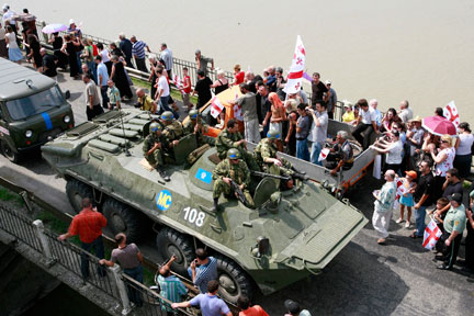 Des soldats russes juchés sur leur véhicule blindé passent sur un pont à Poti, port à l'ouest de la Géorgie sur la Mer Noire, devant des manifestants géorgiens, le 23 août 2008. (Photo : Reuters)