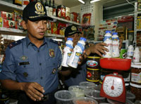 Deux policiers inspectent les bouteilles de lait dans le quartier chinois de Manille, le 24&nbsp;septembre 2008.(Photo : Reuters)