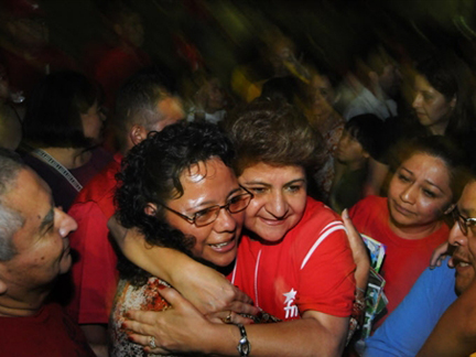 La maire de San Salvador Violeta Menjivar (FMLN) au centre, en rouge, étreint un partisan à San Juan Bello, au sud du pays. Violeta Menjivar espère être réélue. 

		( Photo : AFP )