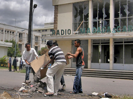 Devant le siège de la radio nationale incendié par des émeutiers, des Malgaches nettoient les débris, le 29 janvier 2009.( Photo : Reuters )