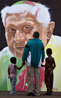 Deux générations devant le portrait peint du Pape Benoît&nbsp;XVI, dont la calotte et la chasuble représentent le drapeau du Cameroun à Yaoundé, le 15&nbsp;mars 2009.(Photo : Reuters)