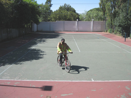 Ian Monzanga faisant du vélo sur son court de tennis.(Photo : Sarah Tisseyre / RFI)