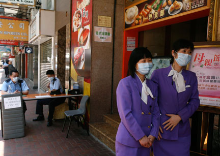Des employés d'un restaurant chinois, chargés de l'accueil des clients, portent des masques de protection, près d'un hôtel où a séjourné le Mexicain testé positif au virus de la grippe A (H1N1), à Hong Kong, le 2 mai 2009.(Photo : Reuters)