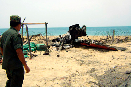 Un militaire sri-lankais observe les restes d'un bateau ayant appartenu aux rebelles tamouls, le 17 mai 2009.( Photo : Reuters )