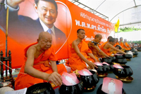 Des moines boudhistes prient devant un grand poster de l'ancien Premier ministre en exil Thaksin Shinawatra, lors de la célébration de son soixantième anniversaire, dans la province de Nonthaburi le 26 juillet 2009.(Photo : AFP)