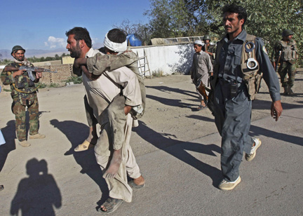 Un Afghan porte un jeune blessé, après l’attaque de talibans sur des bâtiments gouvernementaux, dans la province du Lhogar, au sud de Kaboul, le 10 août 2009. (Photo : Reuters)