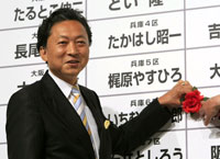 Le leader du Parti démocrate, premier parti d'opposition au Japon, Yukio Hatoyama place une rose sur le nom d'un candidat élu, à Tokyo, le 30 août 2009.(Photo : Reuters)
