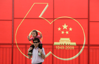 Un homme et sa fille se tiennent devant la bannière célébrant le 60e anniversaire de la création de la République Populaire de Chine, le 27 septembre 2009. (Photo : Stringer / Reuters)