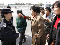 Một nữ công an Trung Quốc đang nghe những người biểu tình phản đối chính sách trưng thu nhà cừa, Bắc Kinh, ngày 19/03/2009Ảnh : Reuters