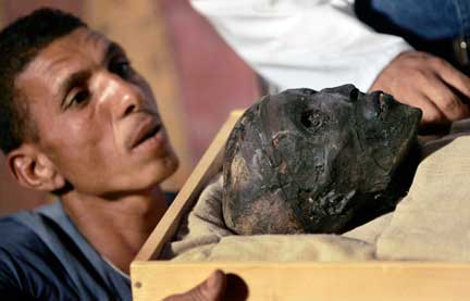 Un employé du service égyptien des Antiquités retire la momie de Toutankhamon de son cercueil. Le public pourra désormais voir le visage de l'enfant-pharaon, à travers une paroi de plexiglass.(Photo : Reuters)