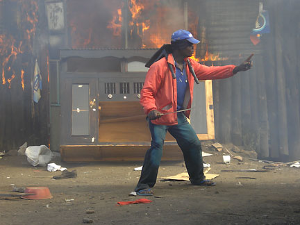 Un membre du groupe d'autodéfense devant une maison incendiée.(Photo : Stéphanie Braquehais/RFI)