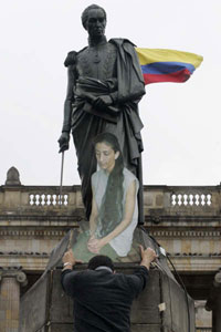 Un manifestant prie en face du portrait d'Ingrid Bétancourt, placé au dessus de la statue de Simon Bolivar, à Bogota.(Photo : Reuters)