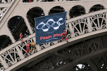 Des pompiers retirent la banderole, détournant les anneaux olympiques, déployée sur la tour Eiffel par des militants de Reporters sans frontières.(Photo : Reuters)