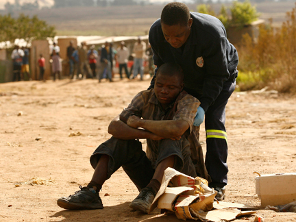 Un policier aide un blessé, à Reigerpark (à l'est de Johannesburg), mecredi 21 mai.( Photo : Reuters )