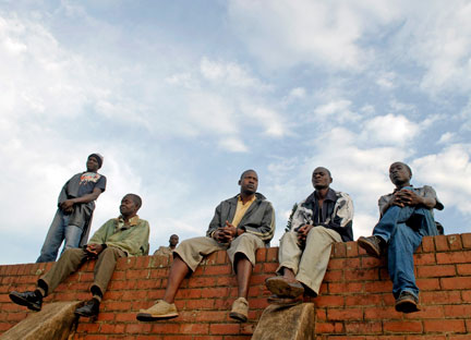 Des immigrés du Malawi, attendent sur le mur du commissariat de police à Durban, le bus qui les ramènera chez eux, le 27 mai 2008.(Photo: Reuters)