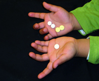 Dans la main gauche de l'enfant, le comprimé unique ASAQ à prendre quotidiennement, contre 4 comprimés journaliers à prendre actuellement.(Source: DNDI)